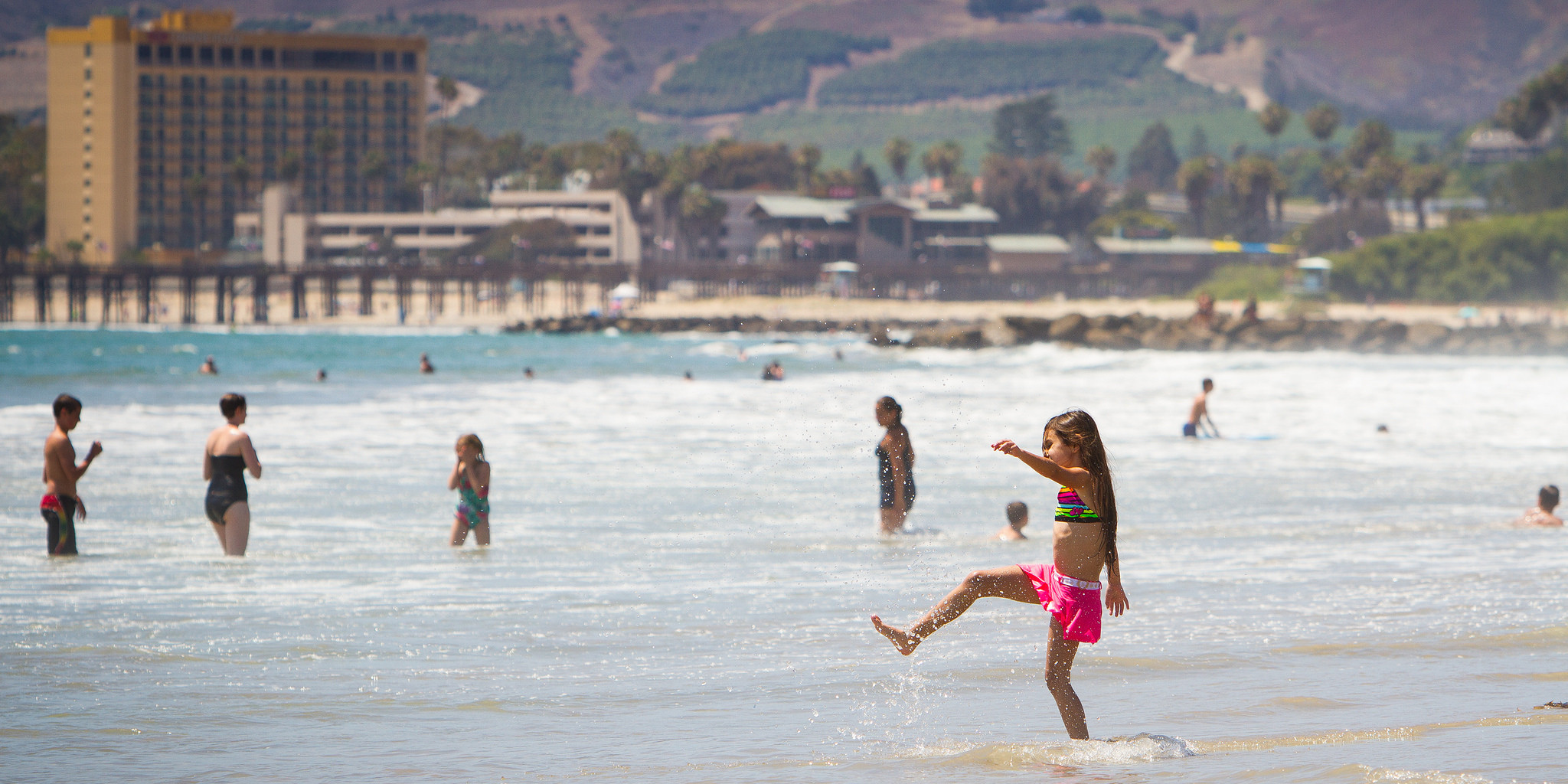 A Year Round Vacation Hotspot: Ventura, CA Little girl splash ocean beach Ventura